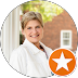 Woman smiling outdoors, white shirt, brick building background, orange star icon.