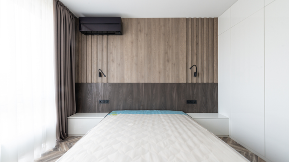 There is a bed in the middle of the room with a wooden headboard.
