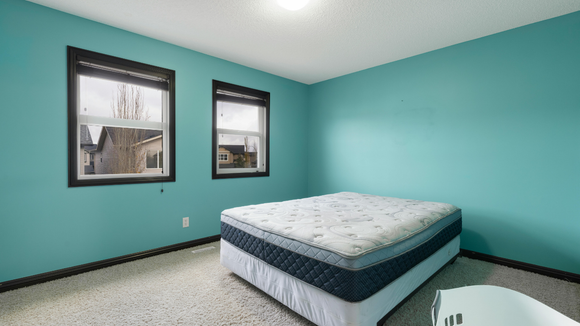 There is a bed in the middle of the room with two windows.