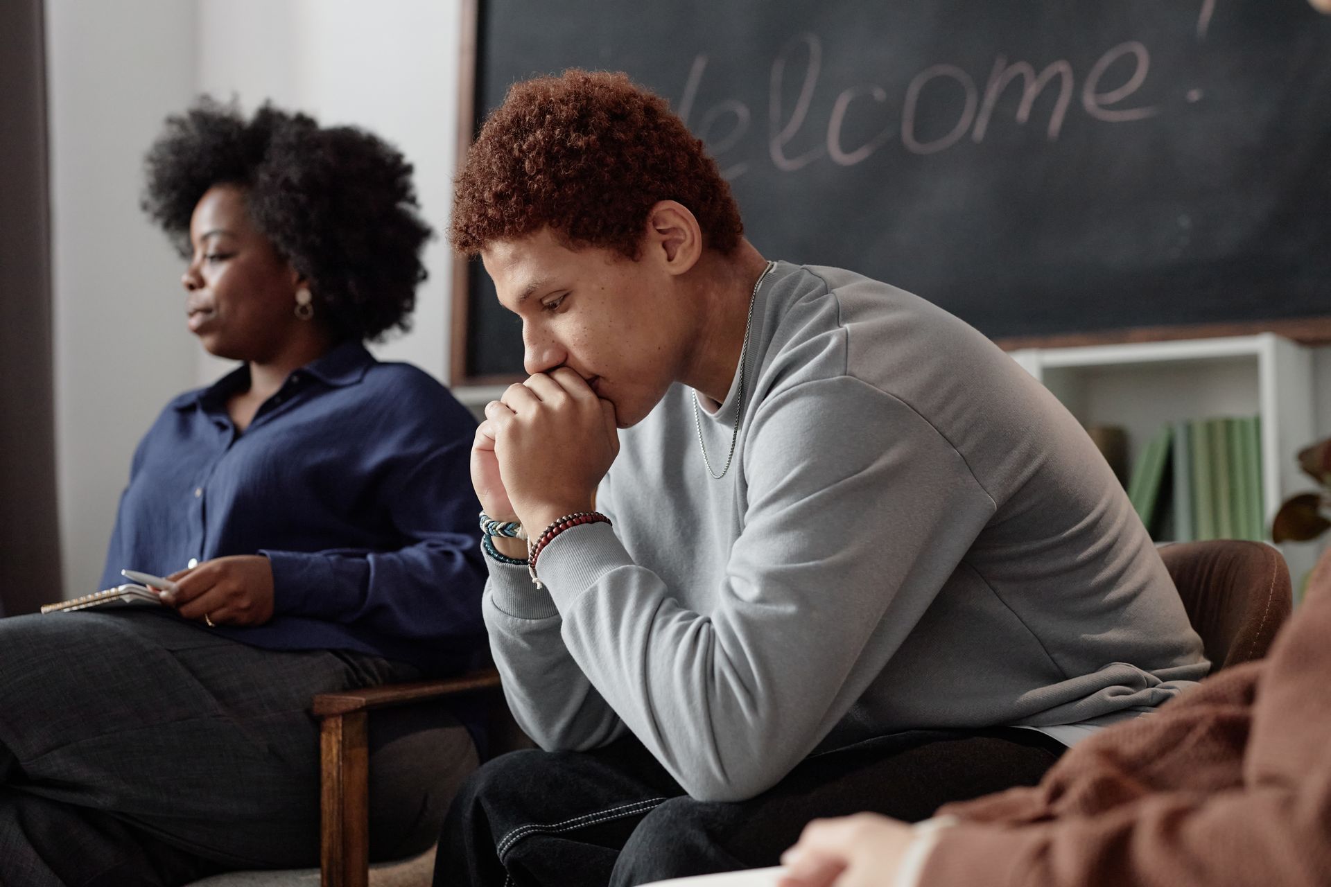 A group of people are sitting in chairs in front of a blackboard.