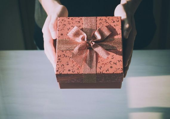 A person is holding a red gift box with a bow.