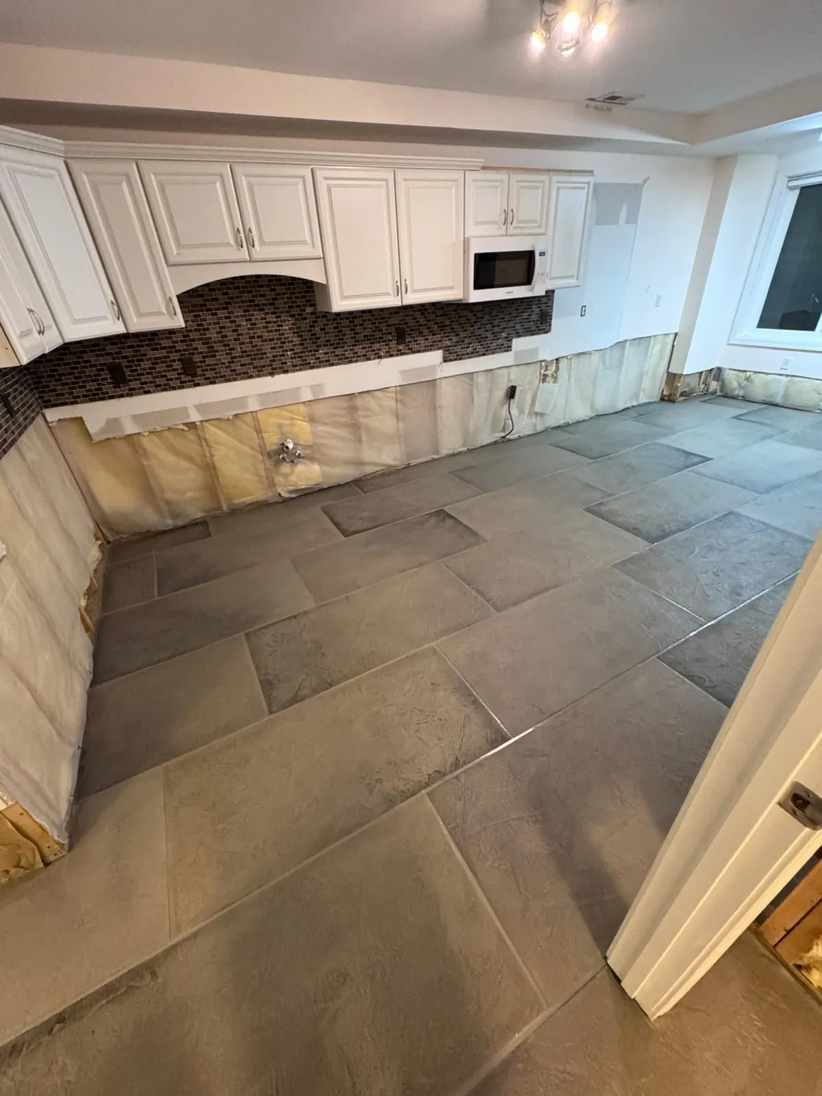 A kitchen with white cabinets and a tiled floor.