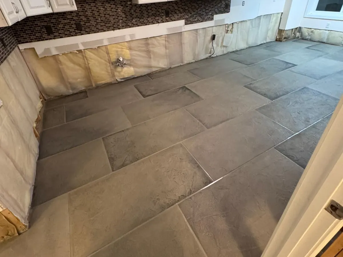 Textured concrete overlay in a modern kitchen with large rectangular tile pattern and white cabinets