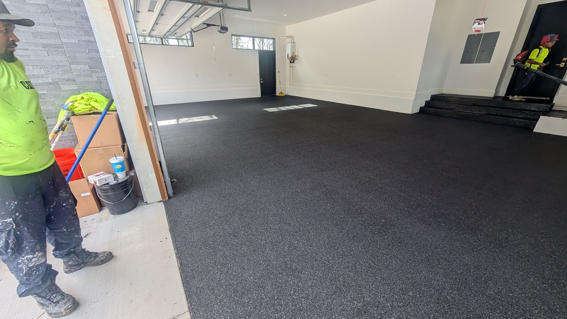 Crew finishing black epoxy flake coating on garage floor installed by Zachary Daniel Concrete in Clinton, SC.