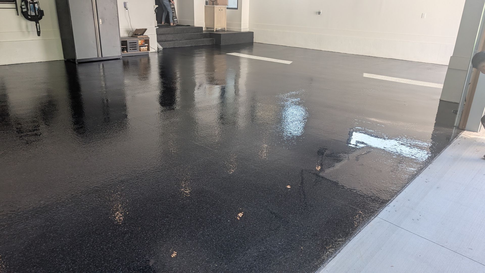Epoxy-coated garage floor with a glossy black finish in a residential property in Greenville, SC.