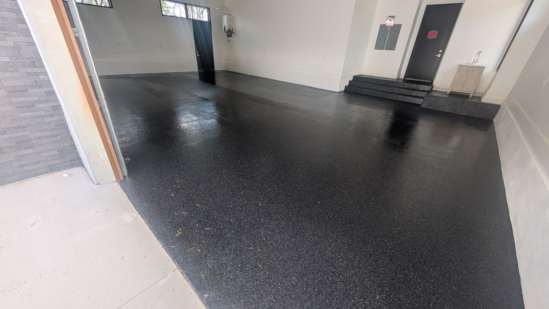 Smooth flake epoxy garage finish near entry door installed by Zachary Daniel Concrete in Greenwood, SC.