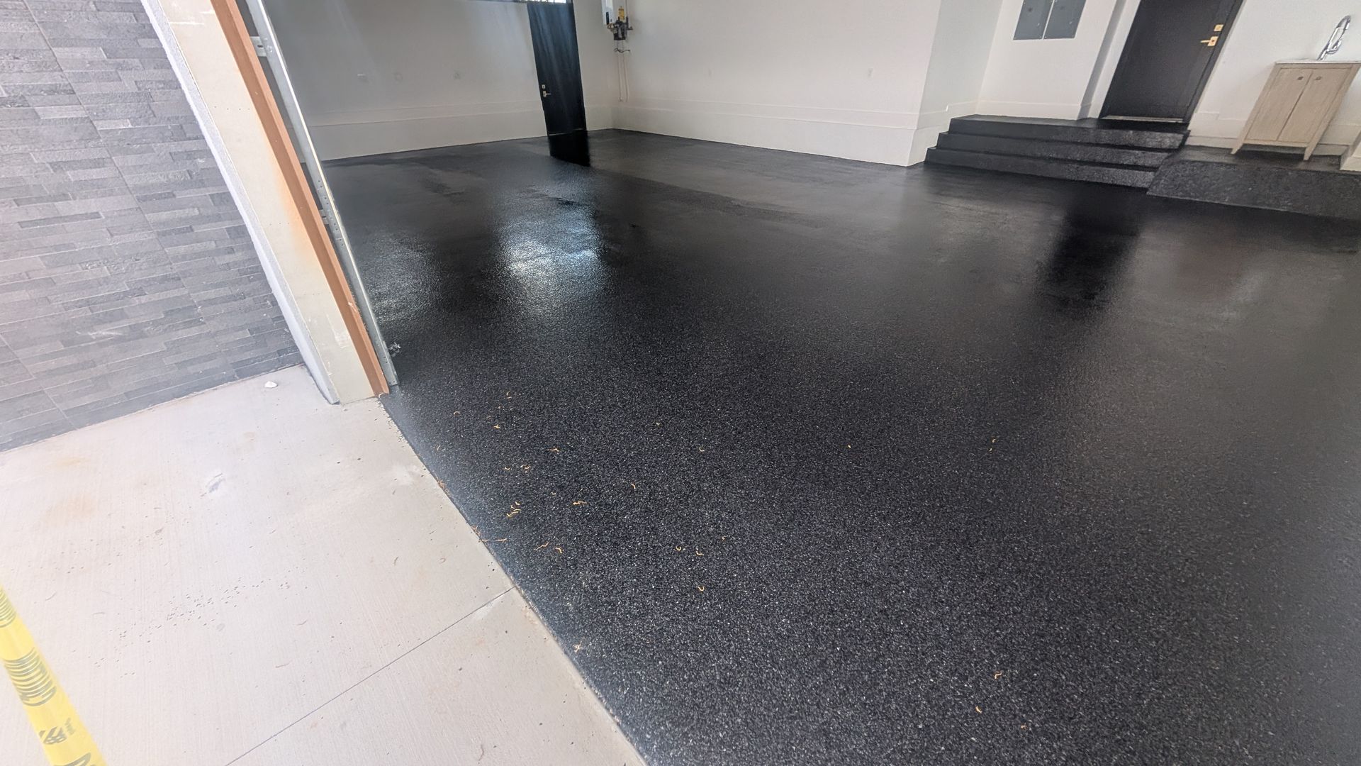 Dark epoxy flake flooring at garage entrance installed by Zachary Daniel Concrete in Waterloo, SC.