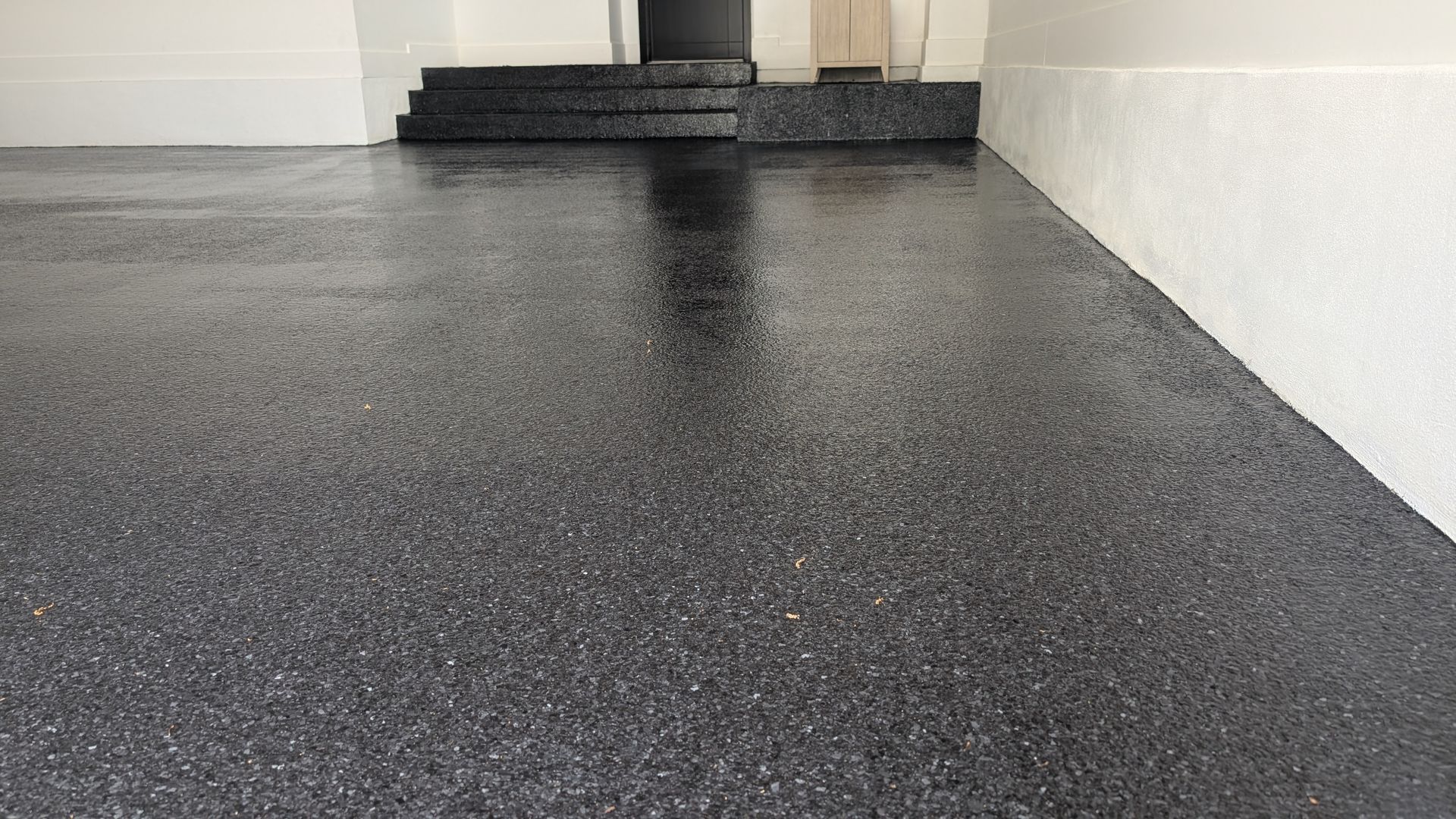 Black epoxy flake floor on entry step landing installed by Zachary Daniel Concrete in Ware Place, SC.