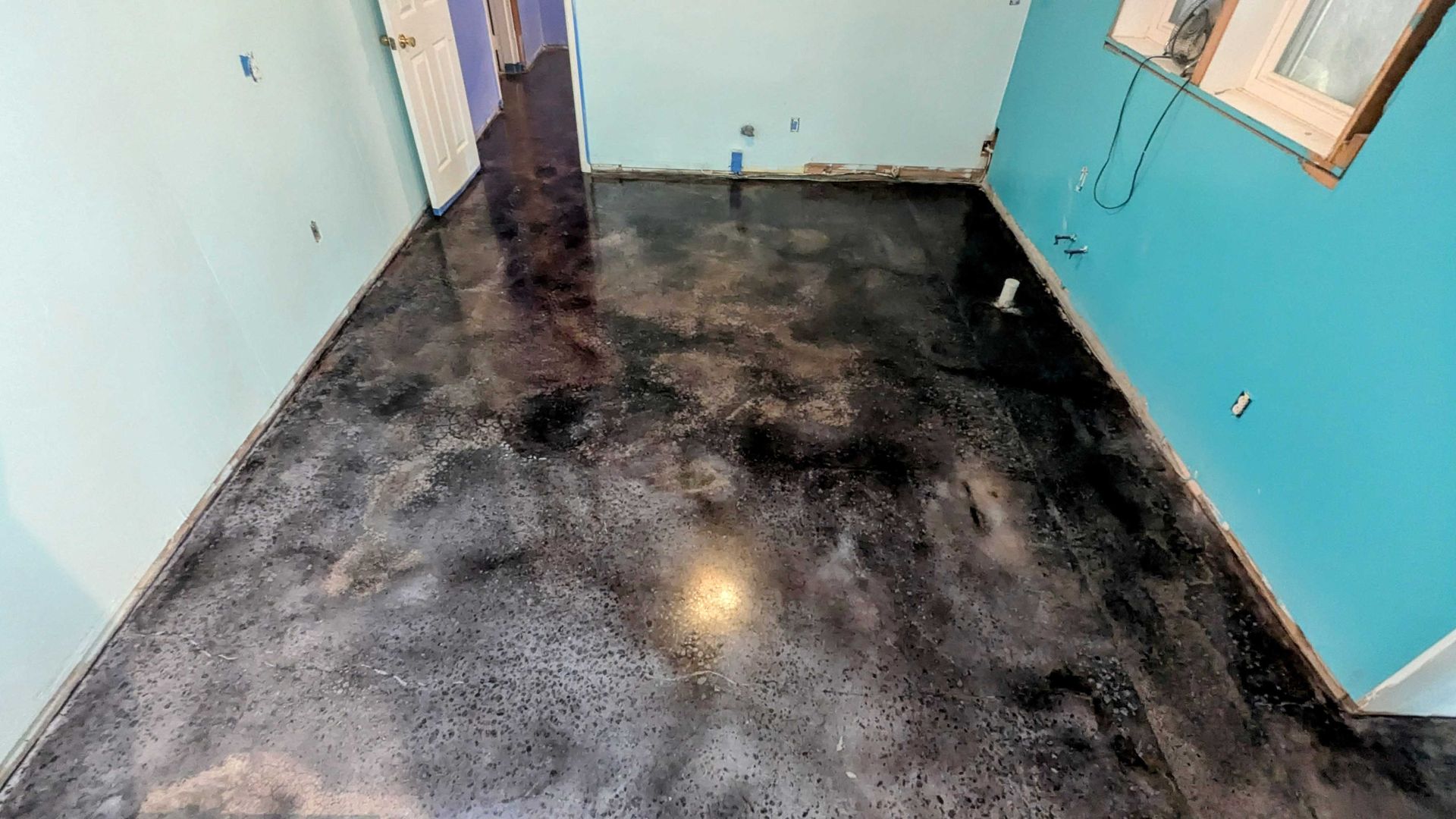 A room with a black concrete floor and blue walls.