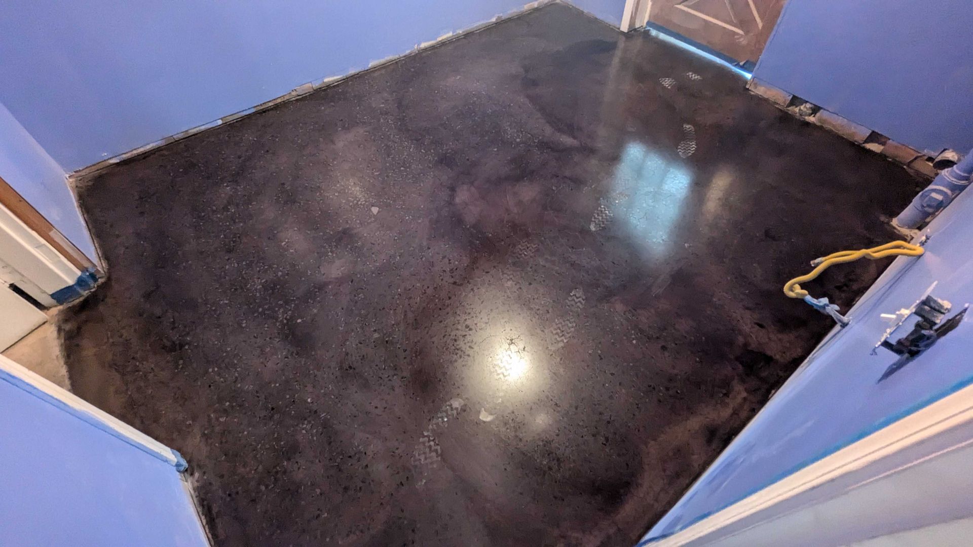 A black concrete floor in a room with blue walls.