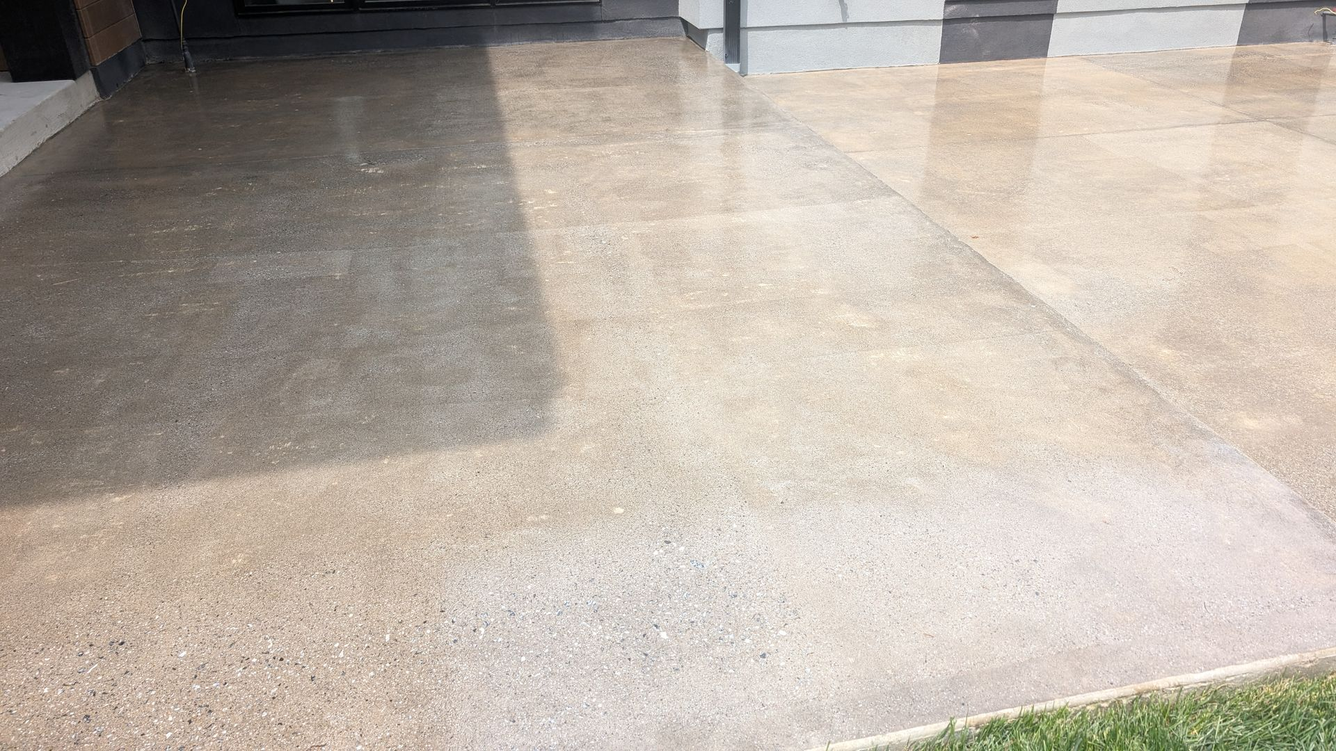 Smooth polished concrete driveway with a light sheen, extending from a modern home's front entry to 