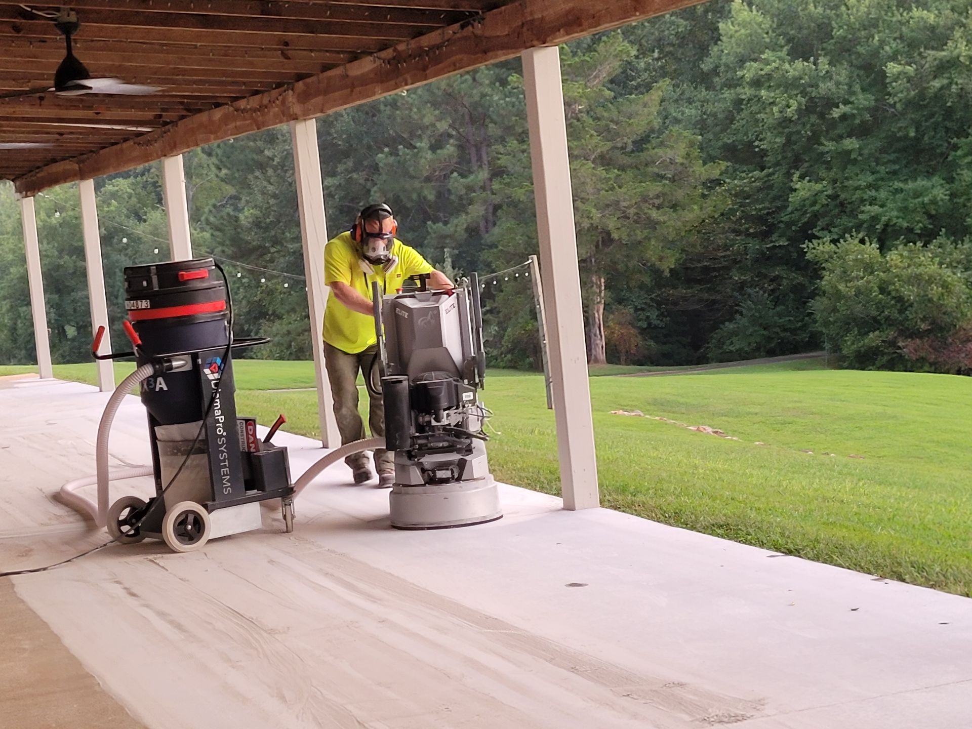 A man is using a machine to grind concrete on a porch.