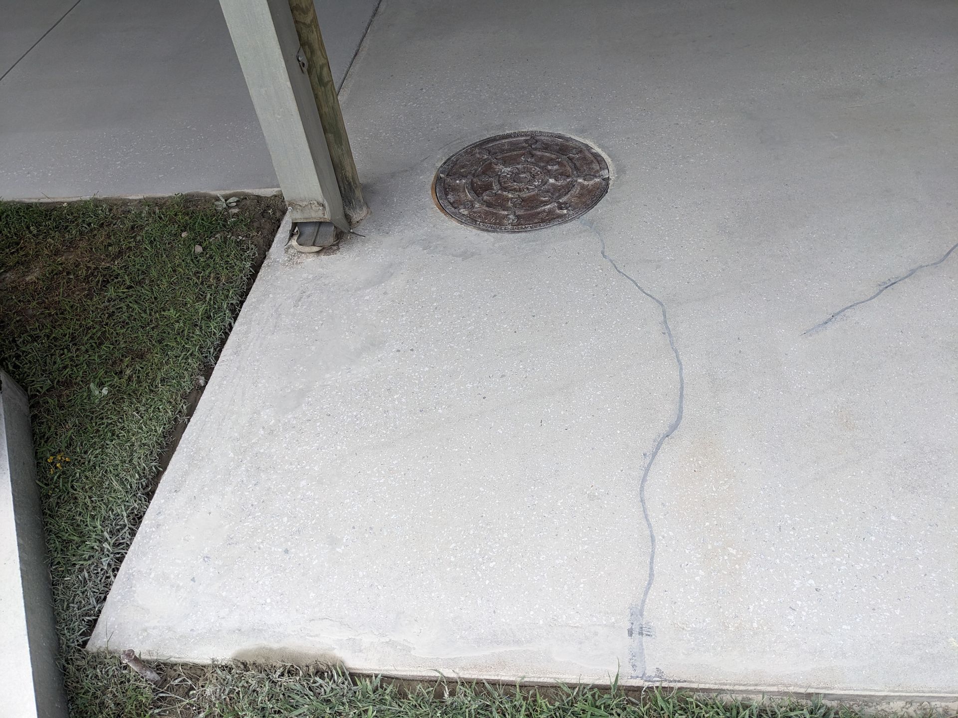 A concrete floor with a manhole cover in the middle of it.