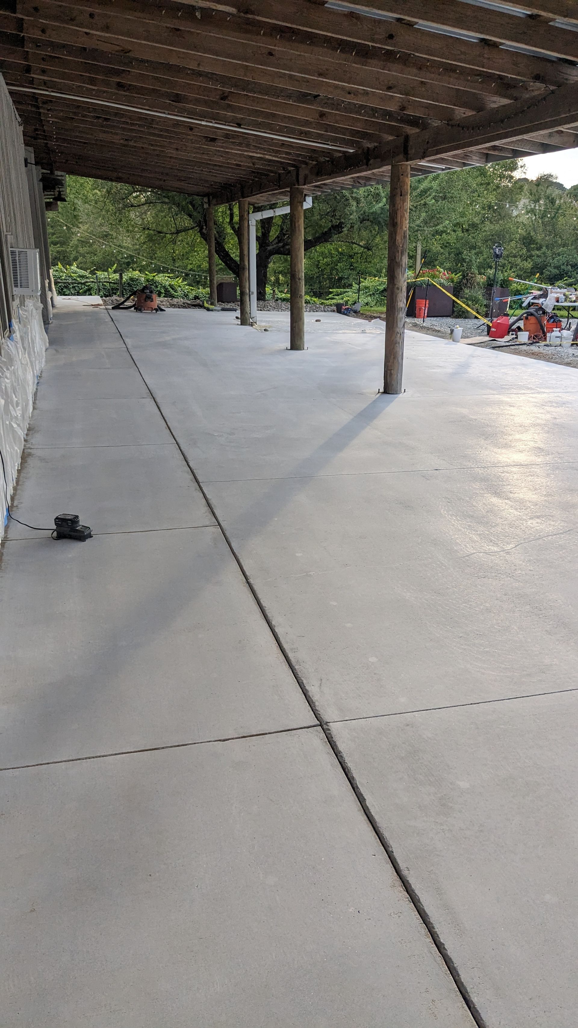 A concrete walkway with a wooden pergola over it.