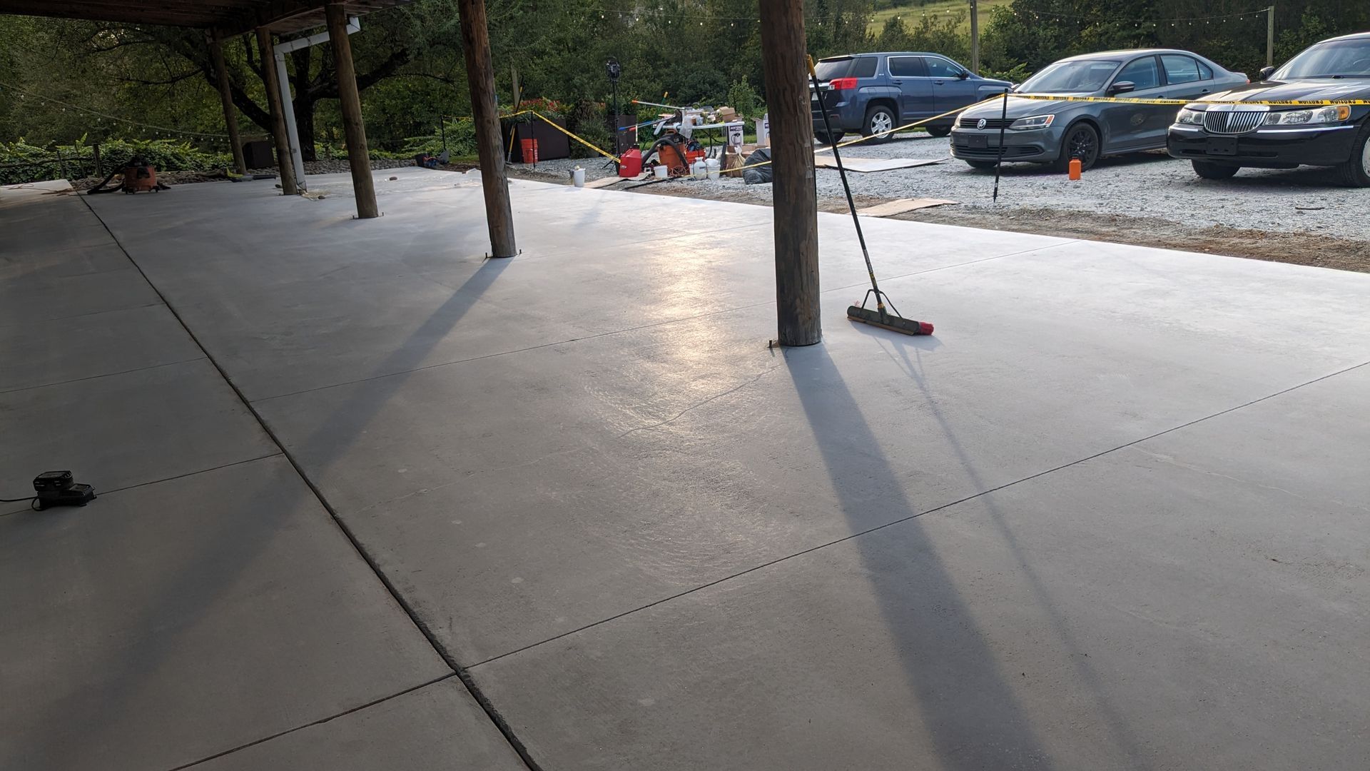 A concrete driveway with cars parked in it and a broom on the ground.