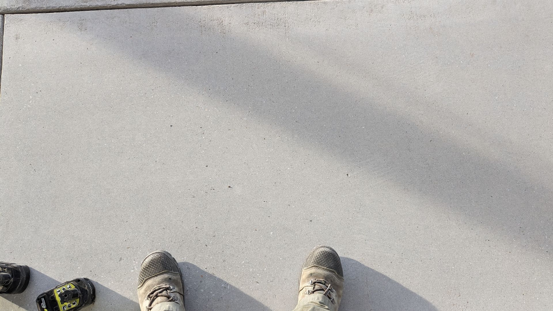 A person 's feet are standing on a concrete surface.