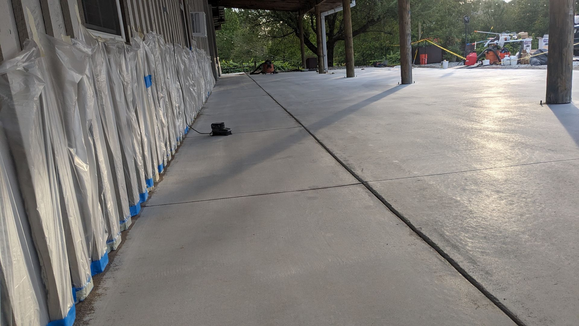 A concrete walkway leading to a house with blue tape on the side of it.