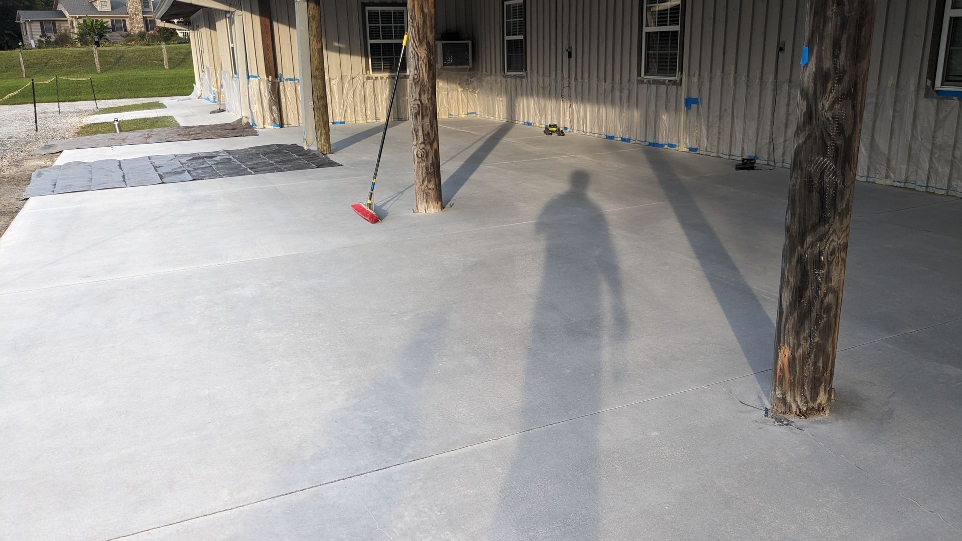 A shadow of a person is cast on a concrete patio.