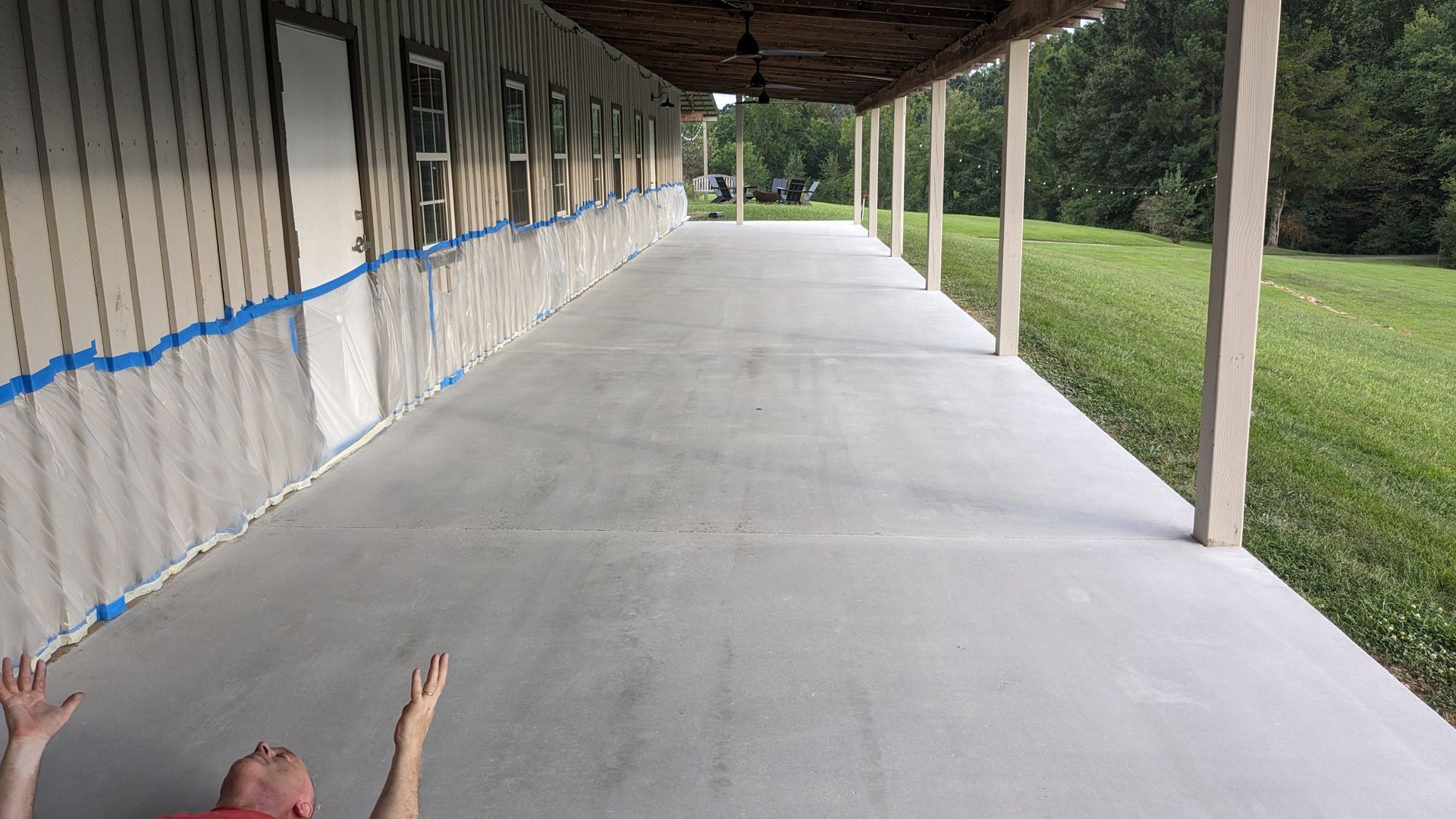 A man is laying on a concrete porch with his arms outstretched.