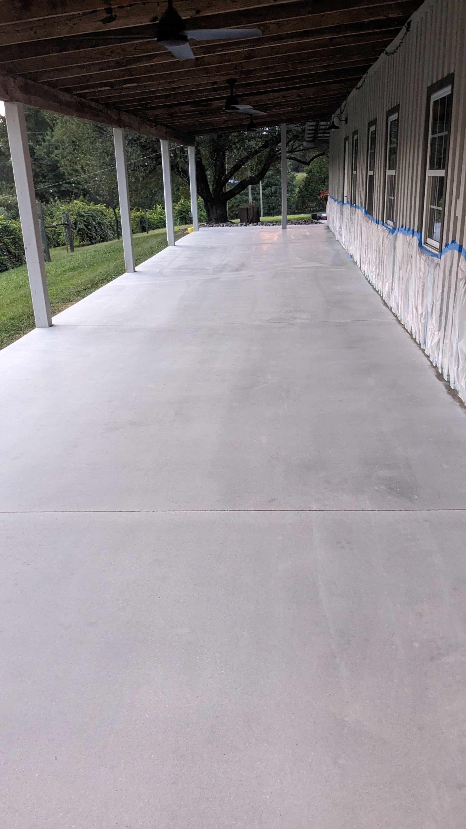 A long concrete walkway leading to a building with a covered porch.