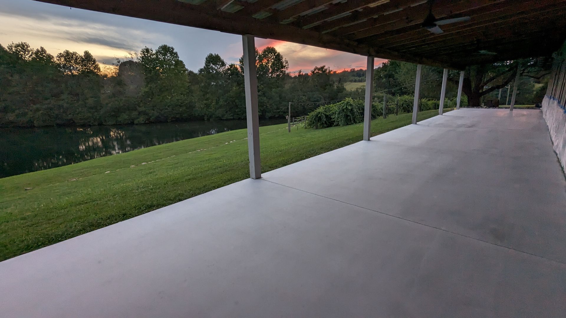 There is a large covered porch with a view of a lake.