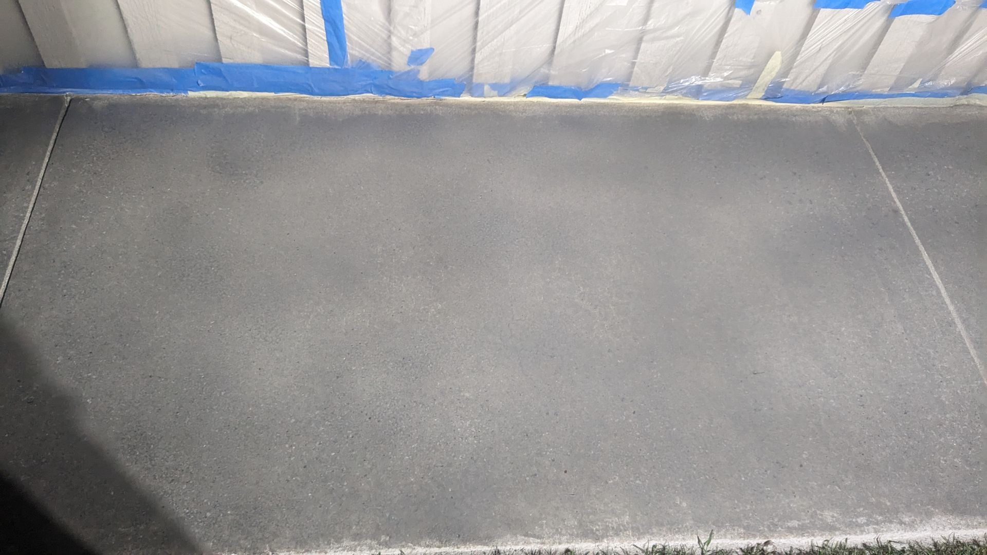 A gray tile floor with a blue tape on the wall.