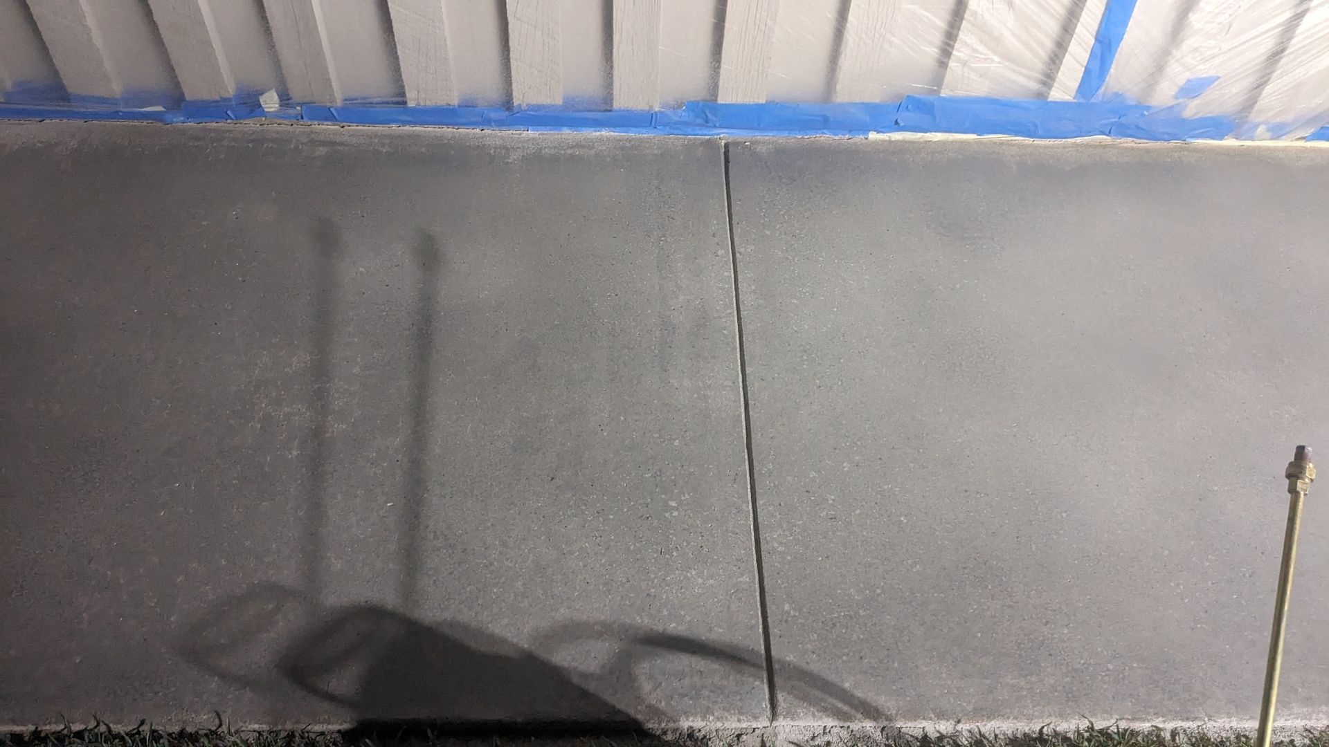 A shadow of a person is cast on a concrete sidewalk.