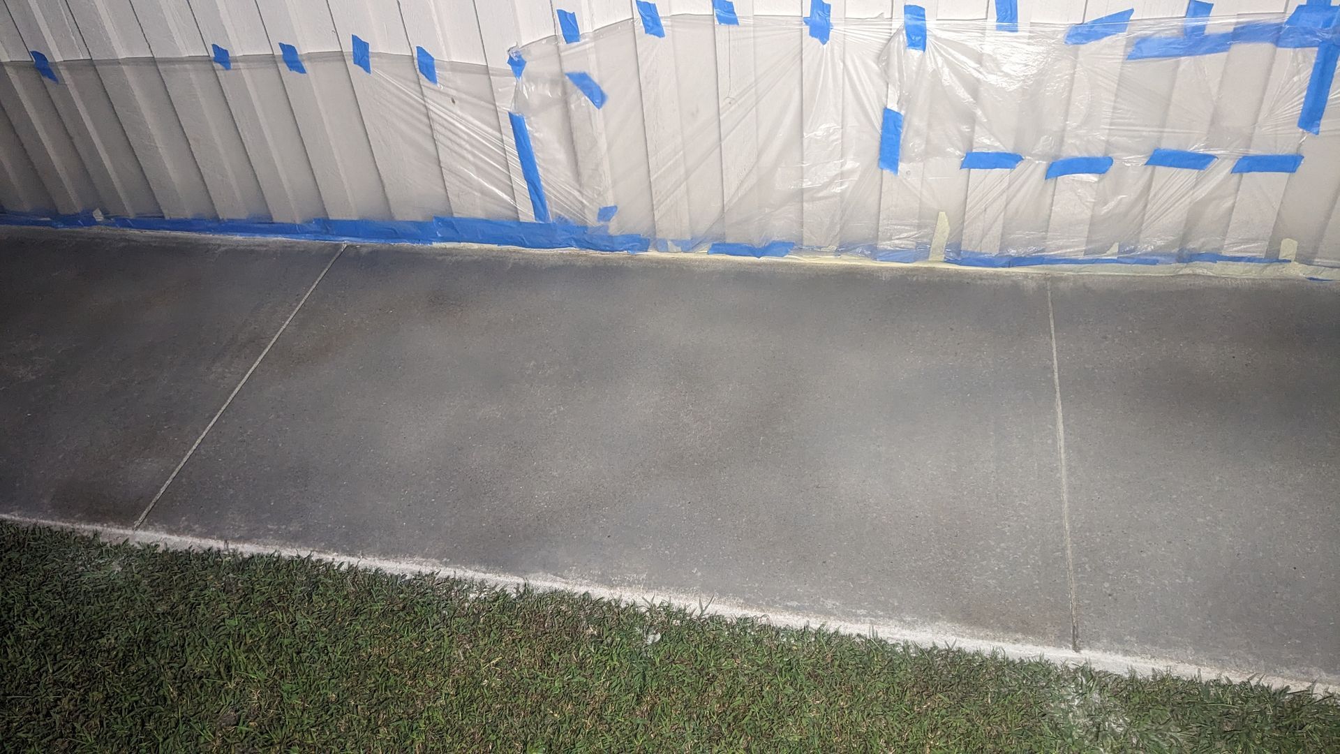 a concrete floor with blue tape on it is being painted .