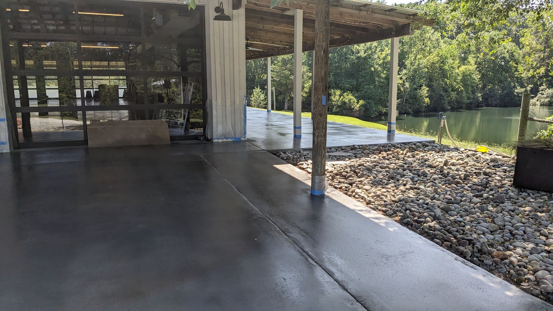 a concrete patio with a pergola and a lake in the background .