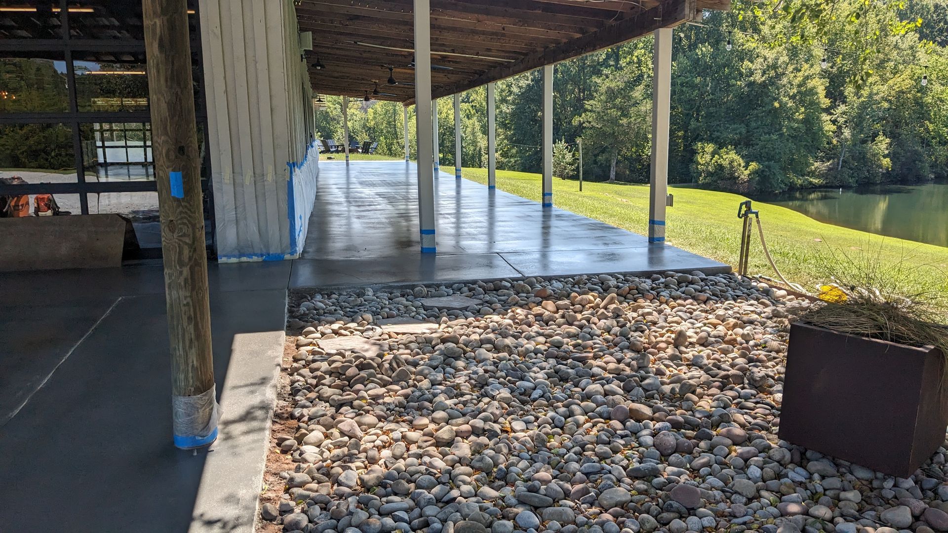 a concrete patio with a covered area and rocks in front of it .