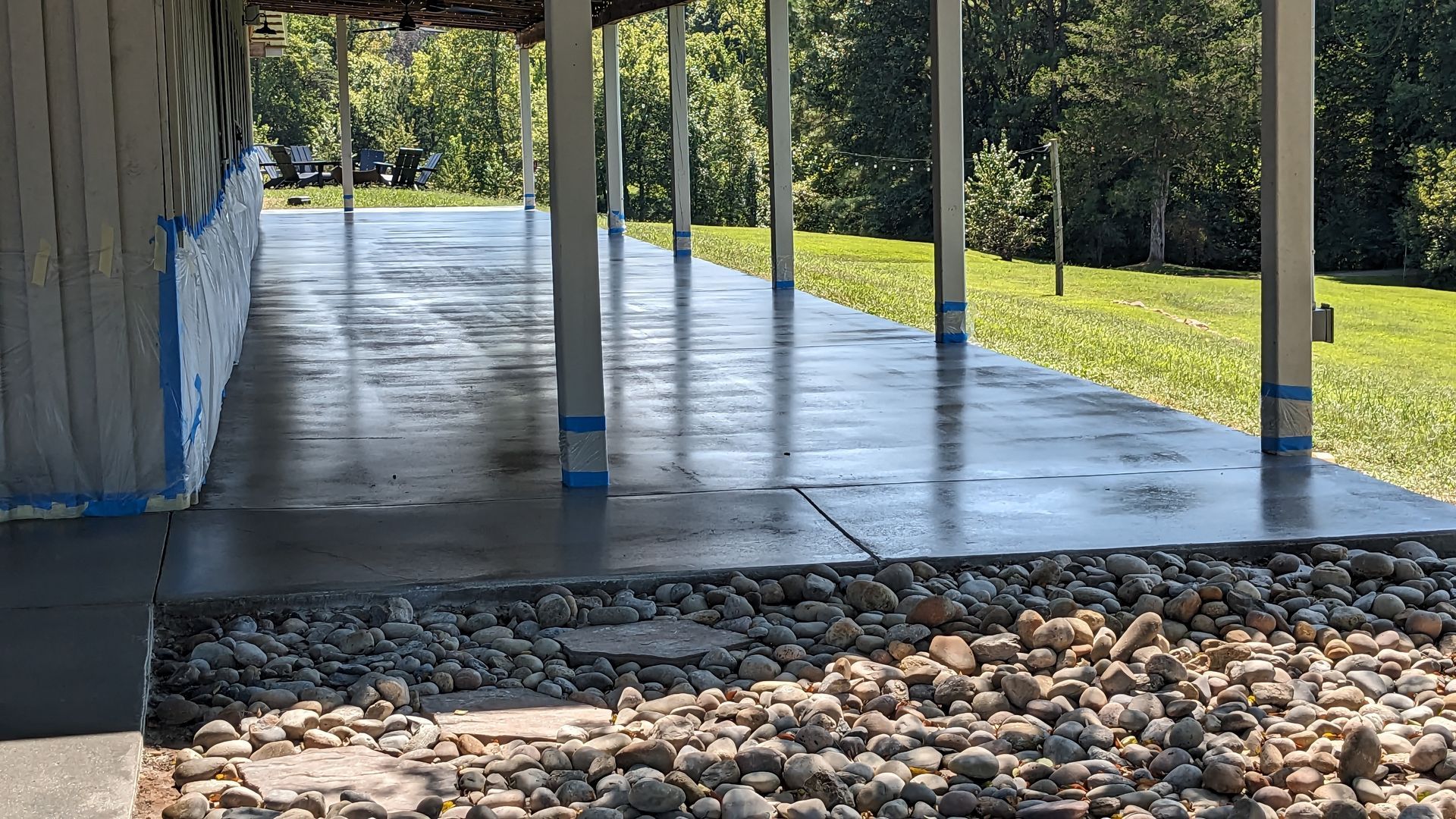 a concrete walkway under a porch with rocks on the ground .
