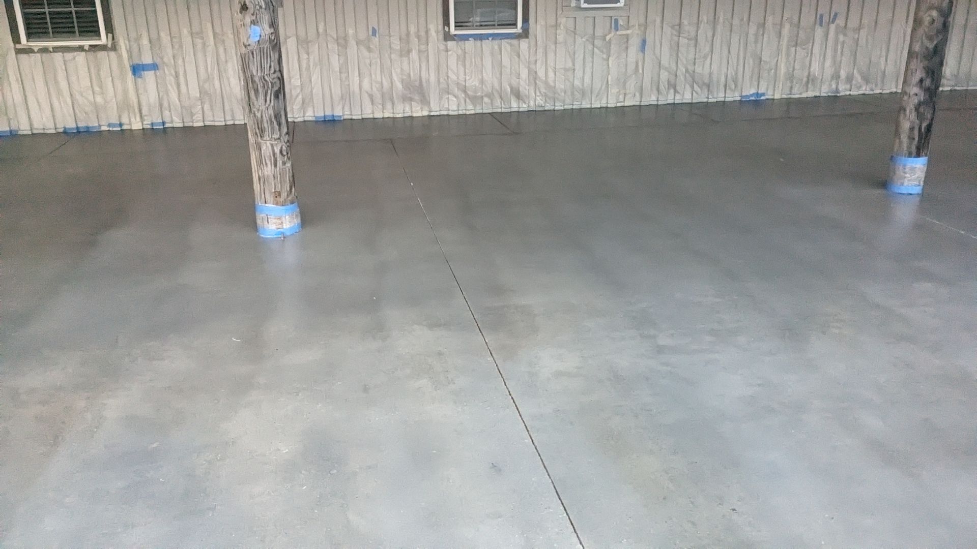 a concrete floor in a garage with pillars and a wooden wall .