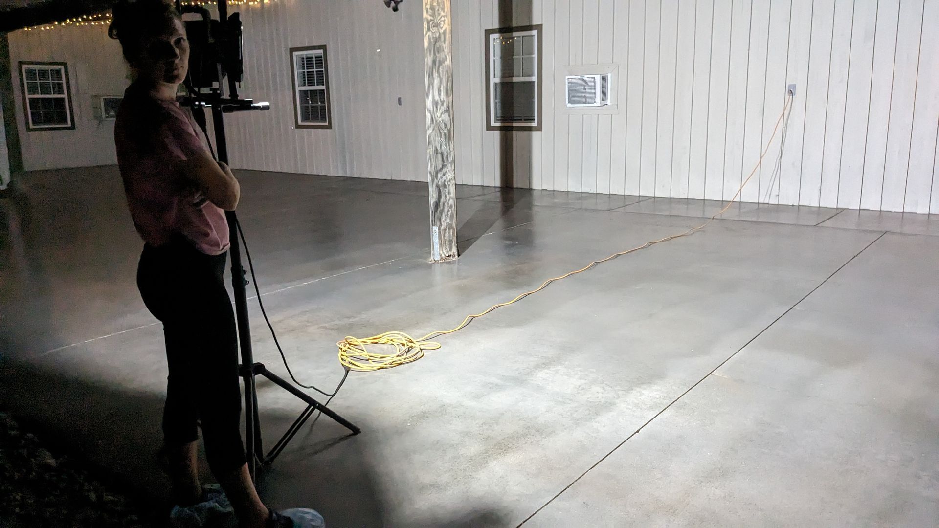 a woman is standing in an empty room with a camera on a tripod .