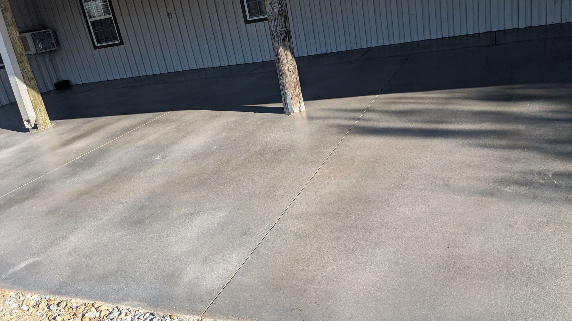 a concrete driveway in front of a house with a tree in the background .