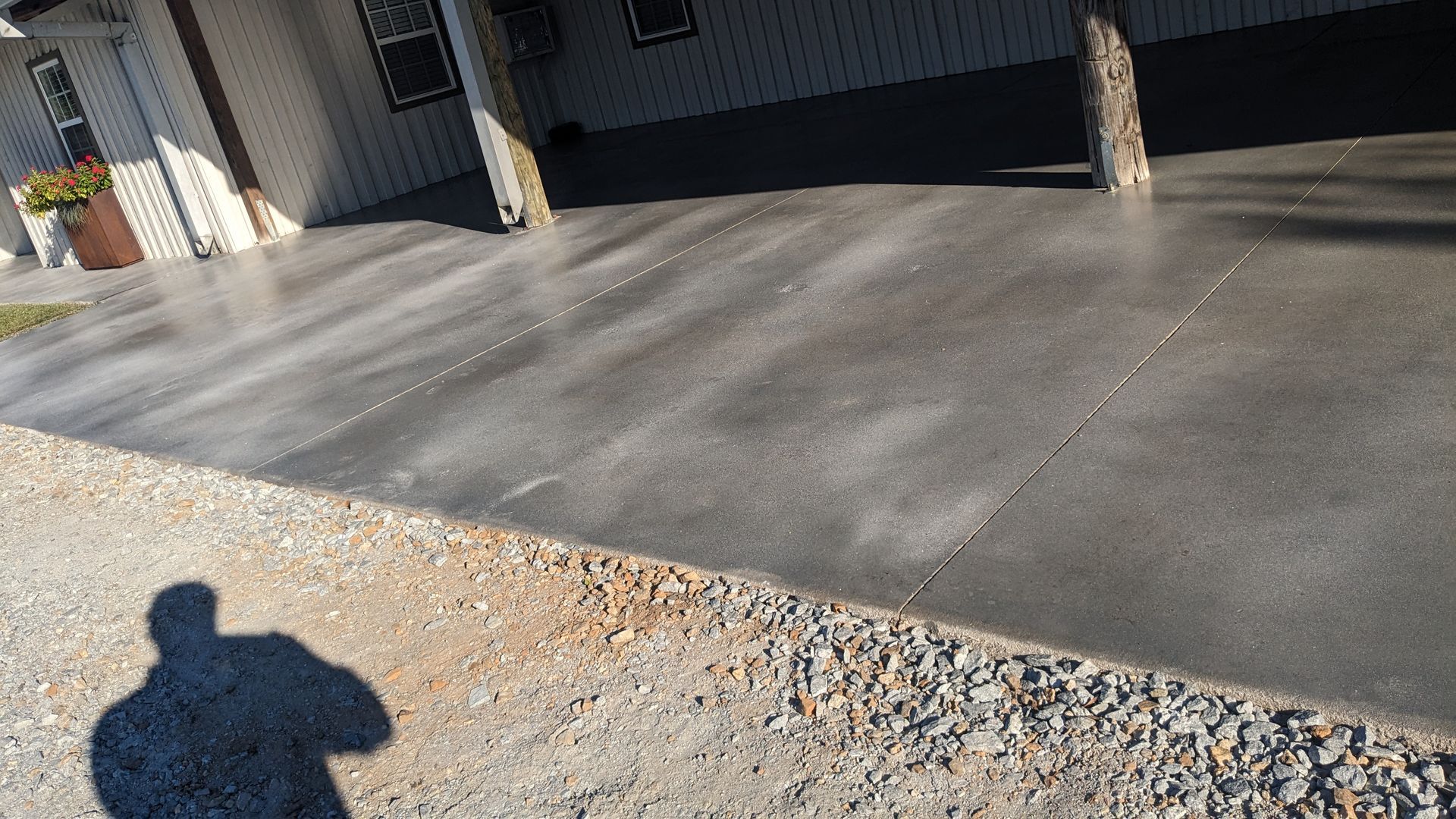 a shadow of a person is cast on a concrete driveway in front of a house .