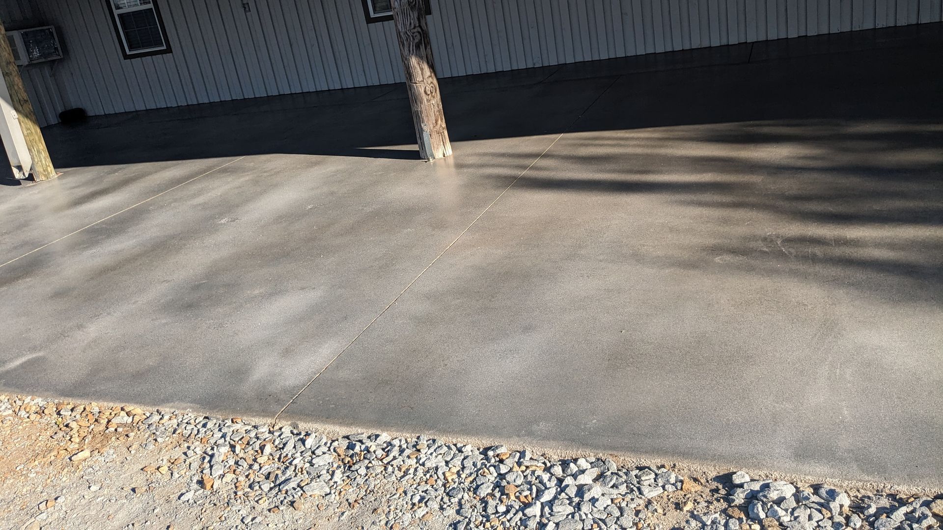 a concrete driveway in front of a house with a tree in the background .