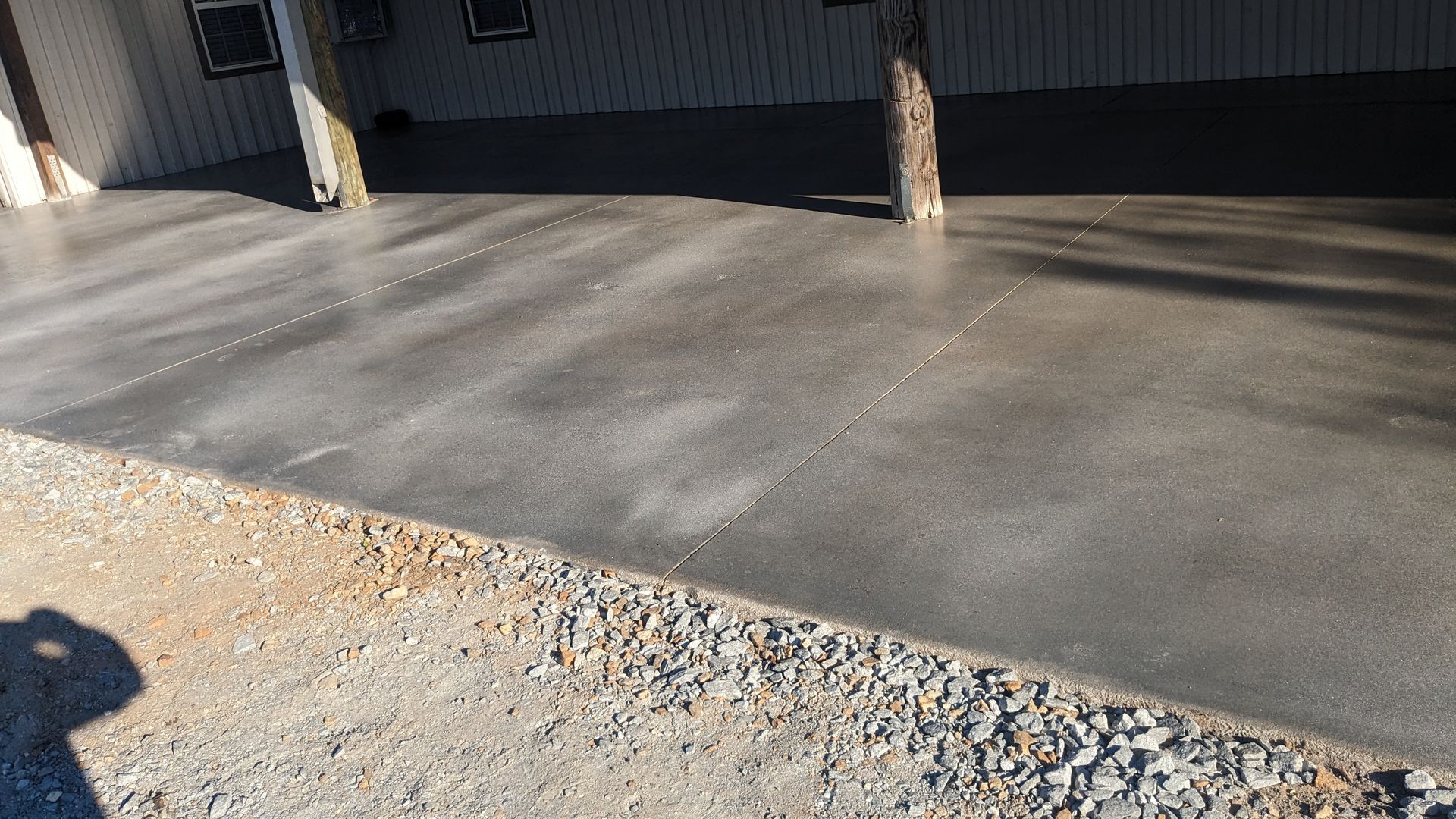 a concrete driveway with gravel in front of a building