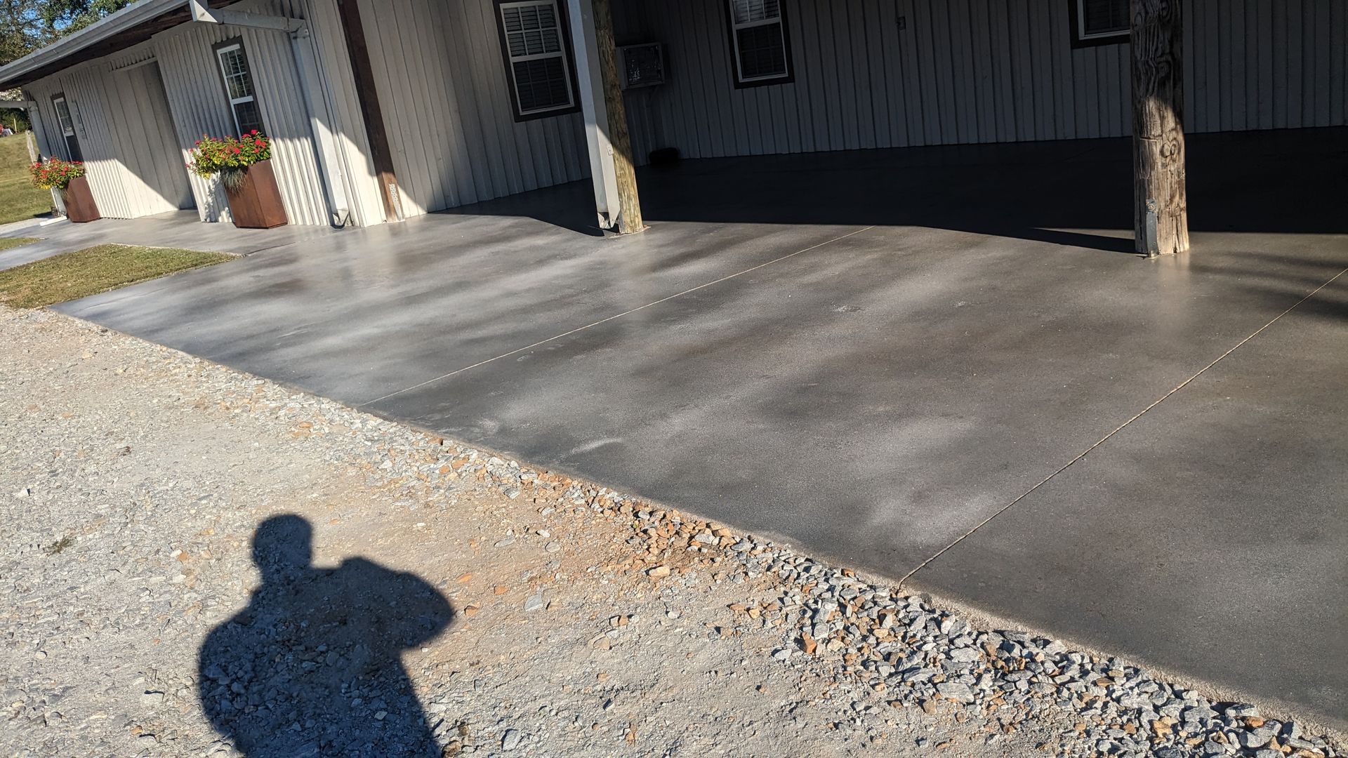 a shadow of a person is cast on a concrete driveway in front of a house .
