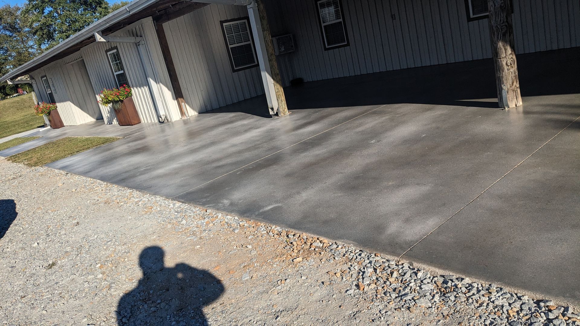 a shadow of a person is cast on a concrete driveway in front of a house .