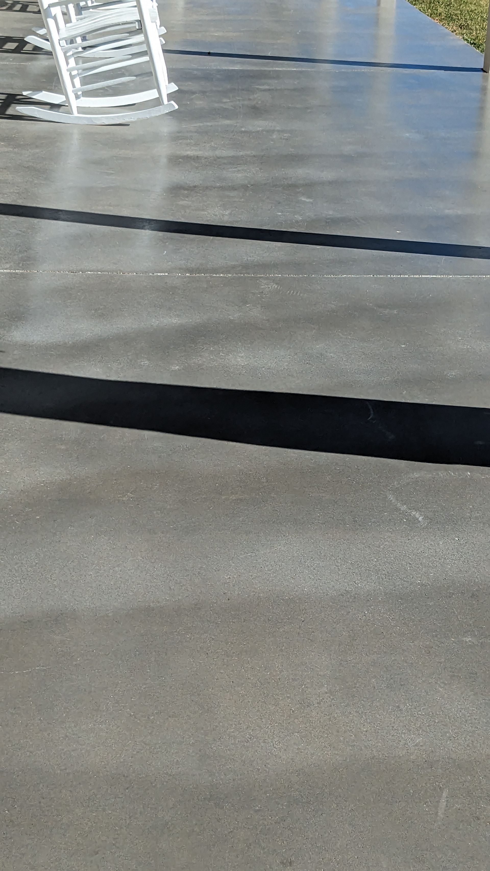a concrete driveway with a rocking chair in the background .