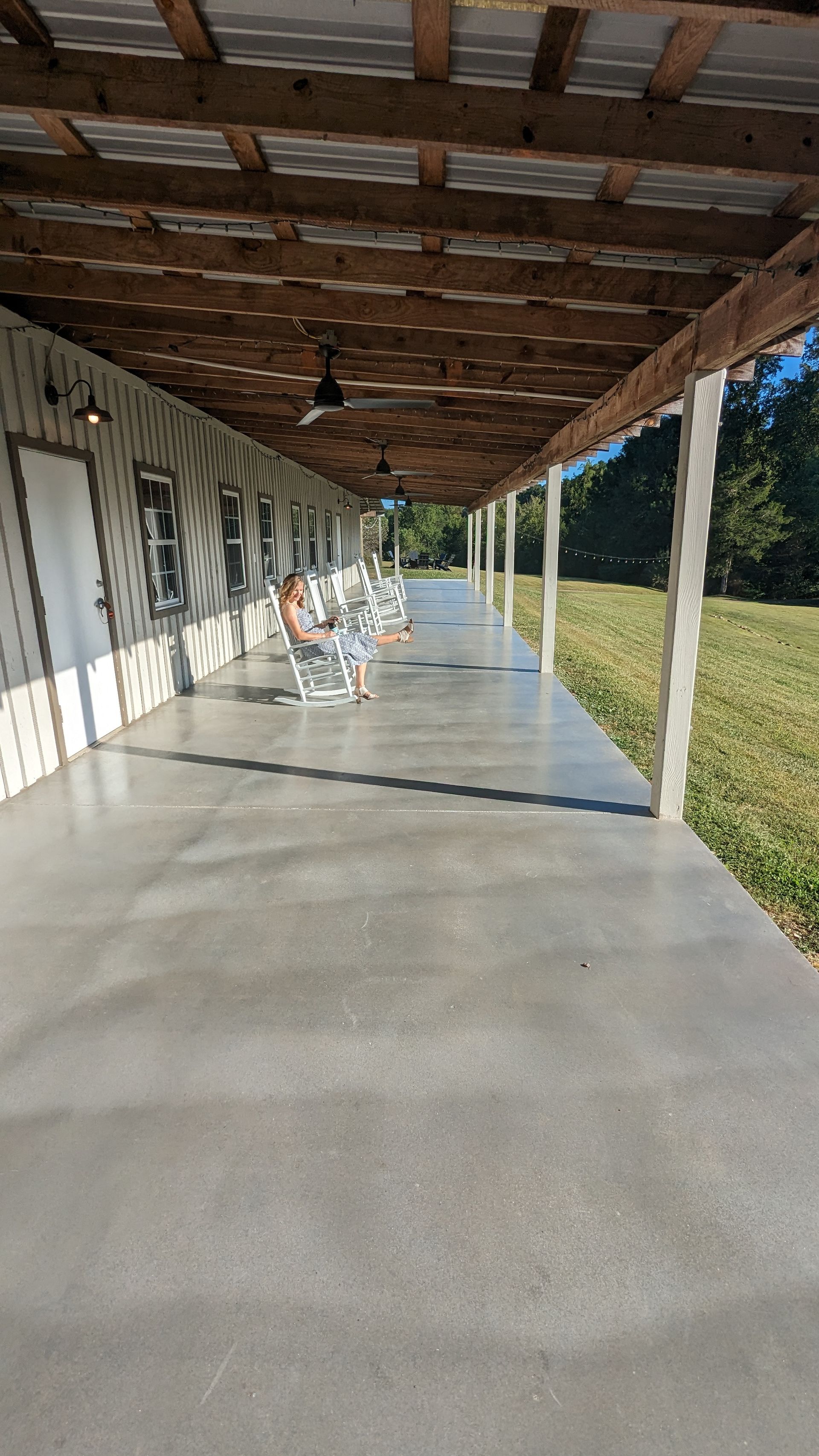 A long covered porch with chairs and a ceiling fan.