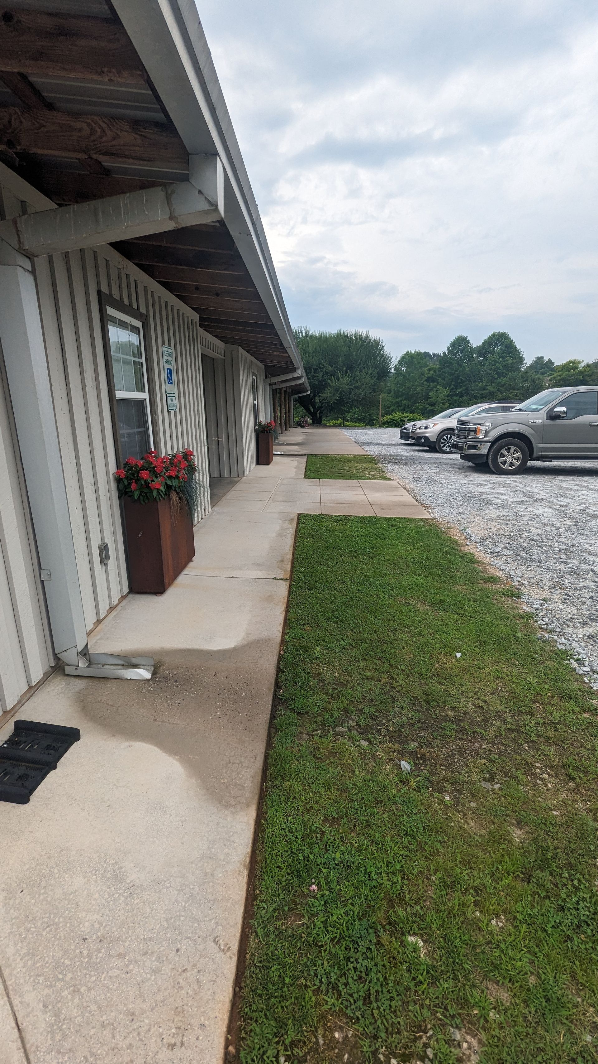 A sidewalk leading to a building with cars parked in front of it.