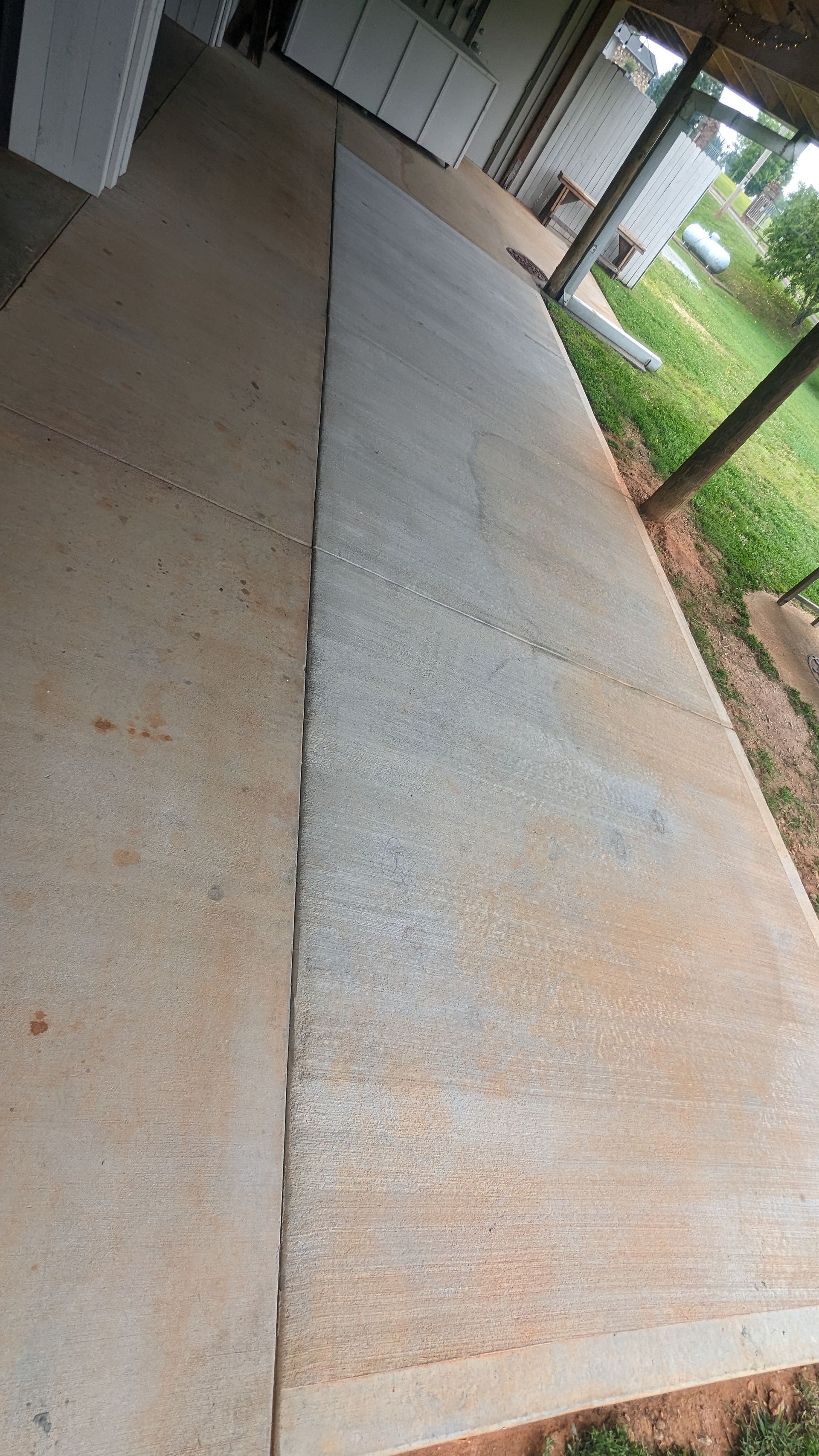 A concrete walkway leading to a house with a covered porch.