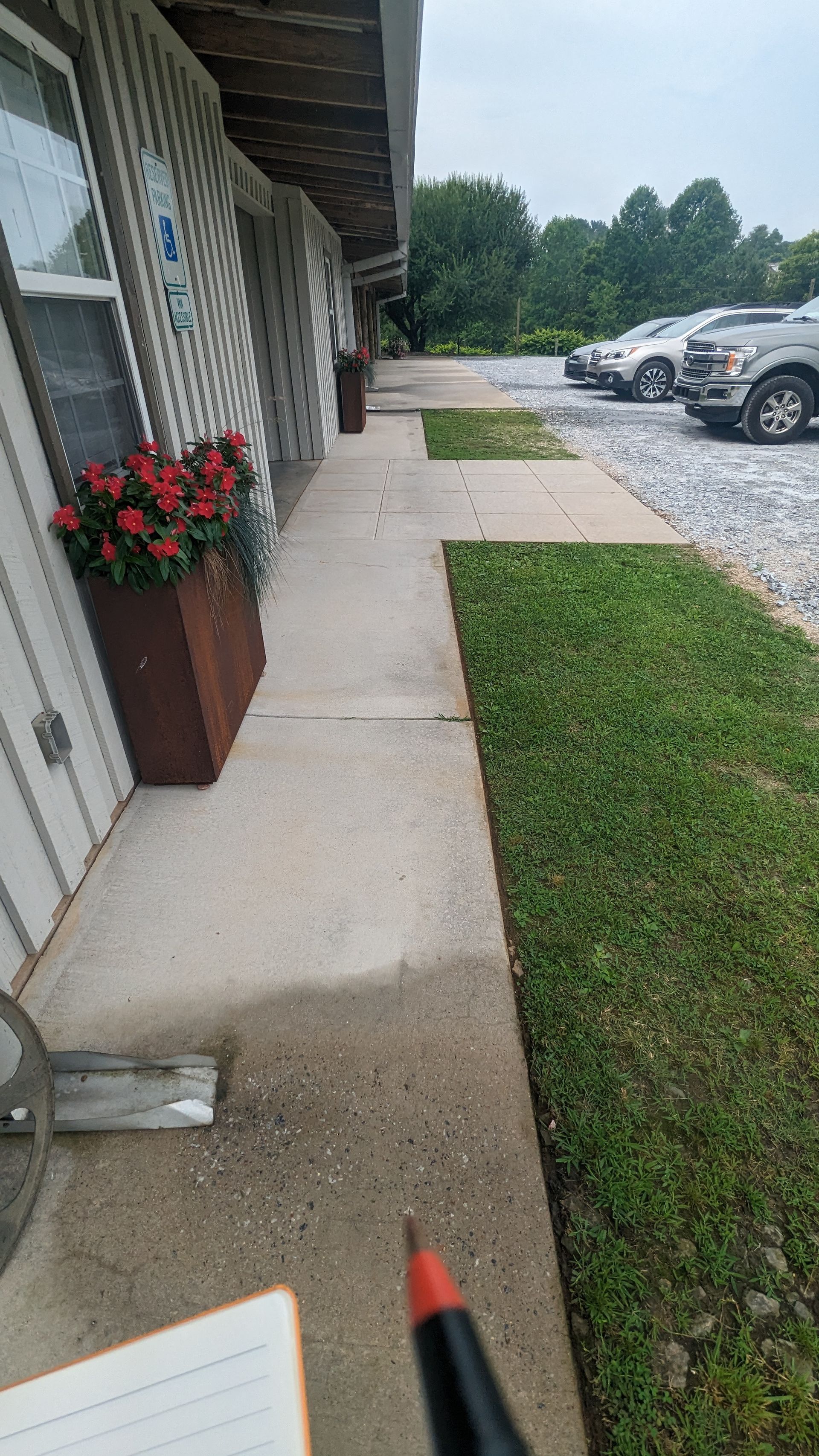 A pencil is sitting on a table next to a sidewalk in front of a building.