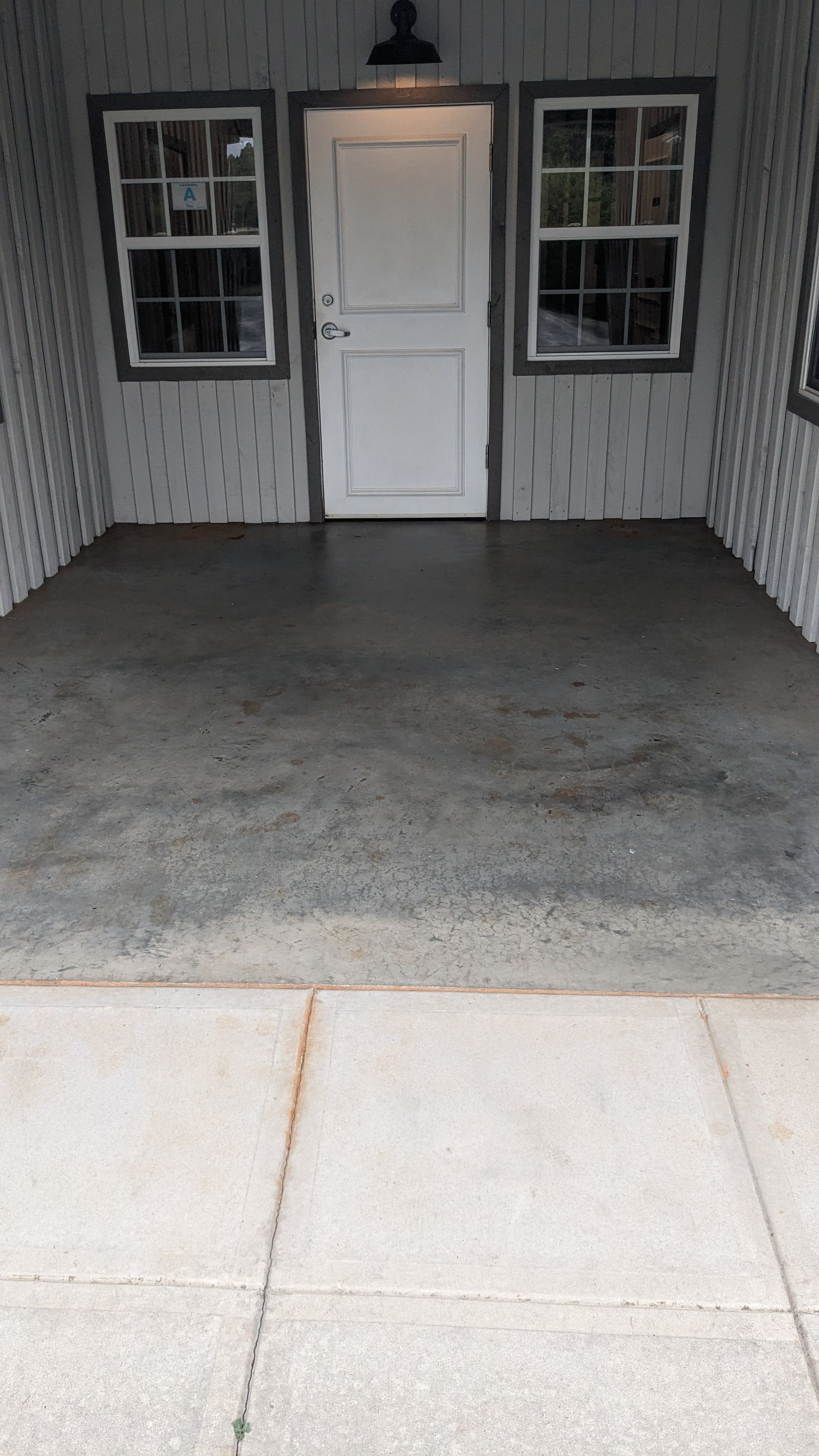 A concrete floor in a garage with a door and windows.