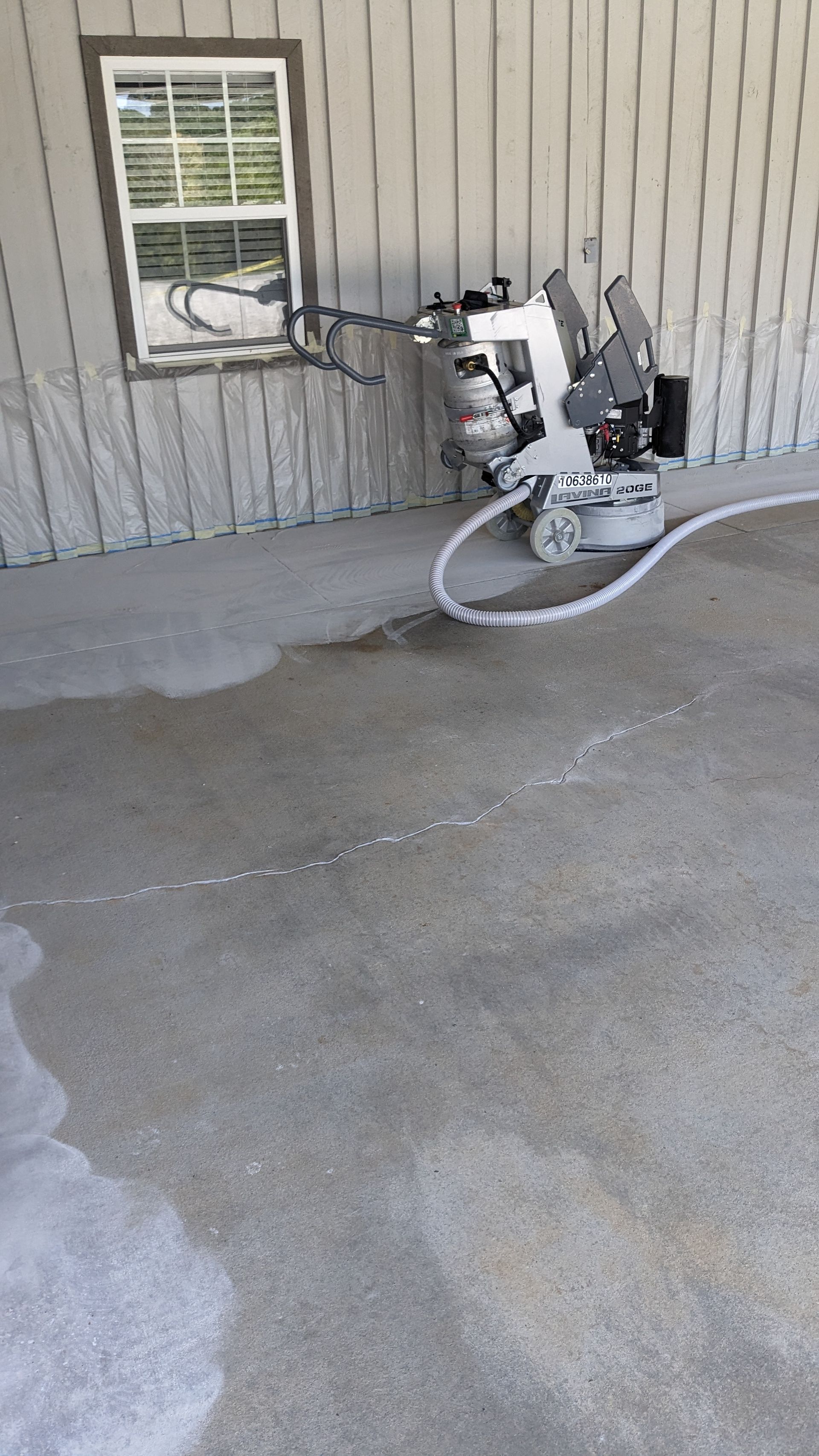 A machine is cleaning a concrete floor in a garage.
