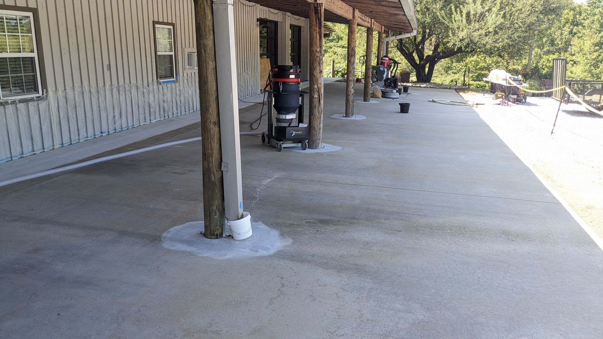 A lawn mower is parked under a covered porch in front of a house