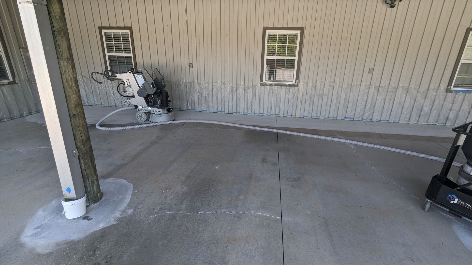 A concrete driveway is being painted in front of a house.