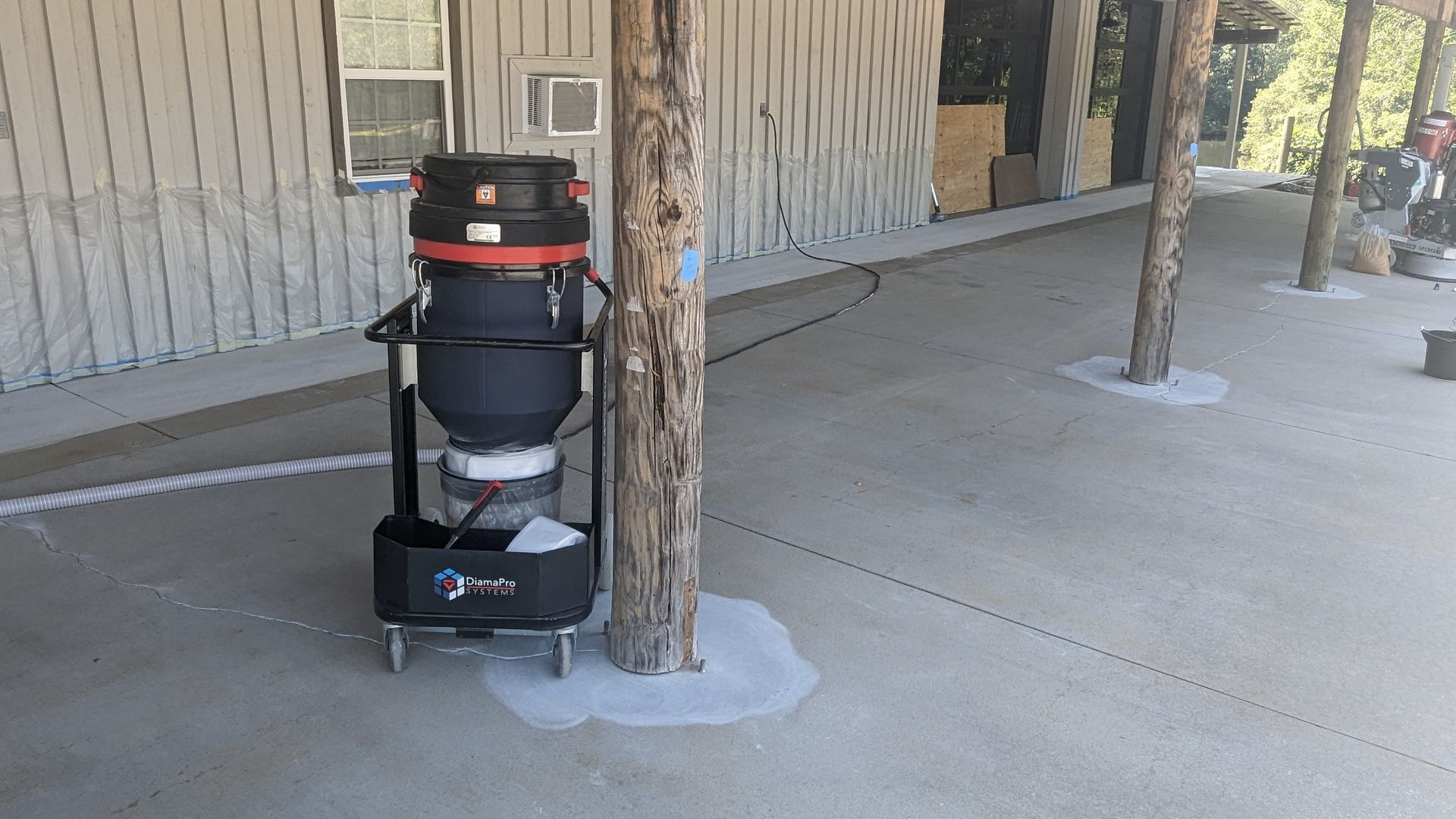 A vacuum cleaner is sitting on a porch next to a tree.