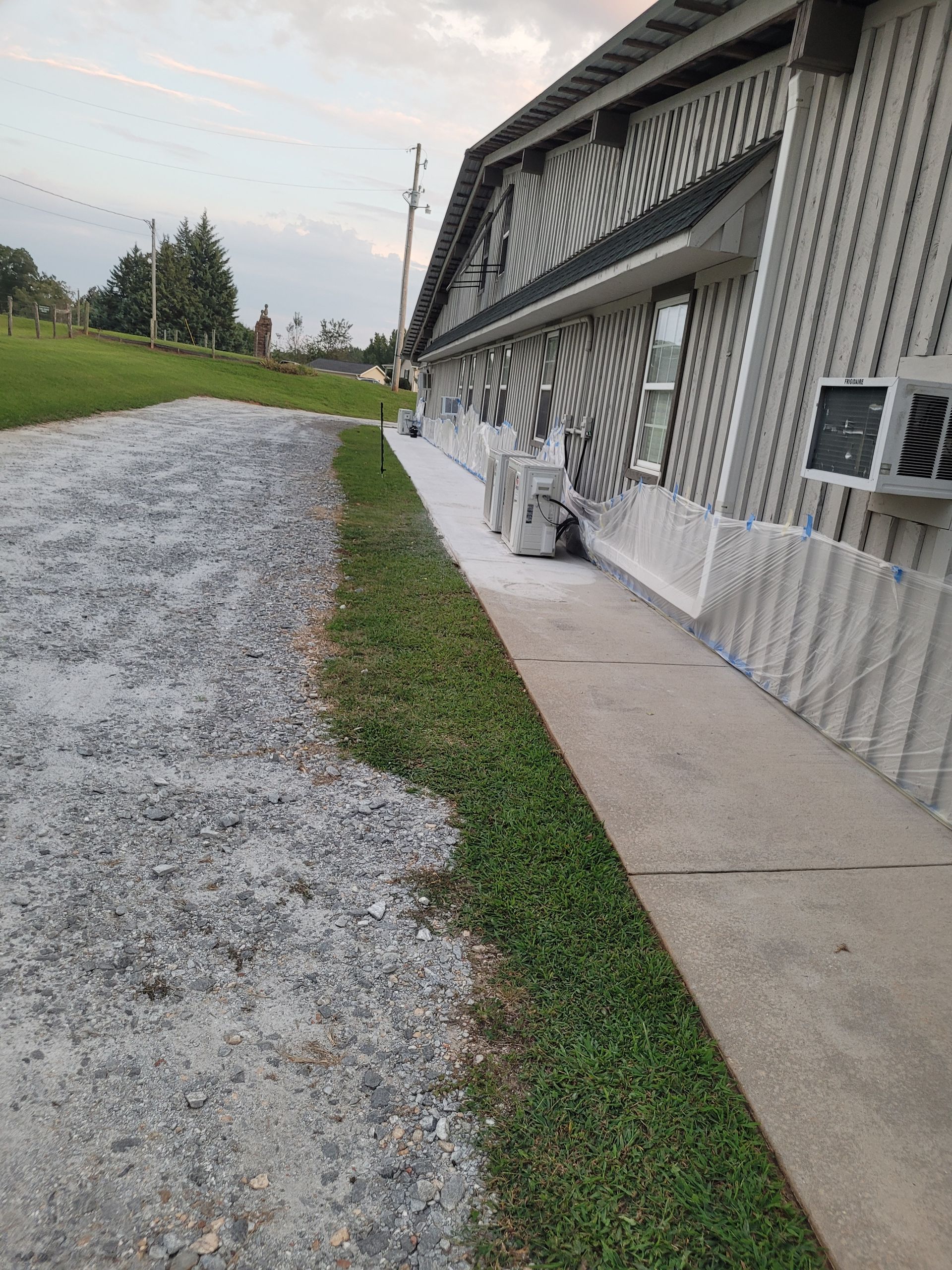 A sidewalk leading to a building with a lot of grass and gravel.